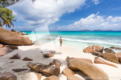 Image of Man enjoying Anse Patates picture perfect beach on La Digue Island, Seychelles.