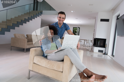 Image of multiethnic couple on an armchair with a laptop