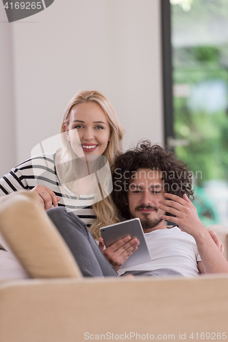 Image of couple relaxing at  home with tablet computers