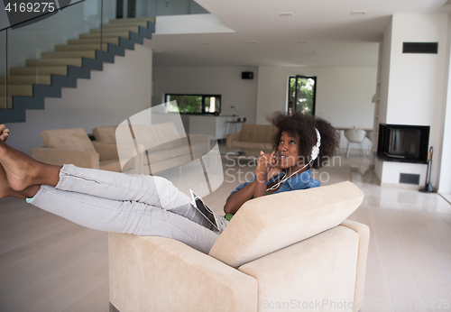 Image of African american woman at home in chair with tablet and head pho