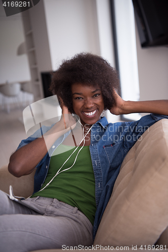 Image of African american woman at home in chair with tablet and head pho