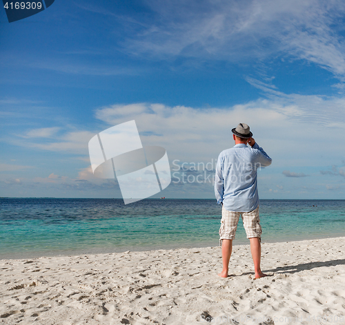 Image of Man walking along a tropical beach in the Maldives.