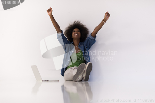 Image of african american woman sitting on floor with laptop