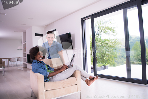 Image of multiethnic couple on an armchair with a laptop