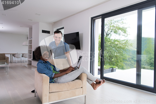 Image of multiethnic couple on an armchair with a laptop