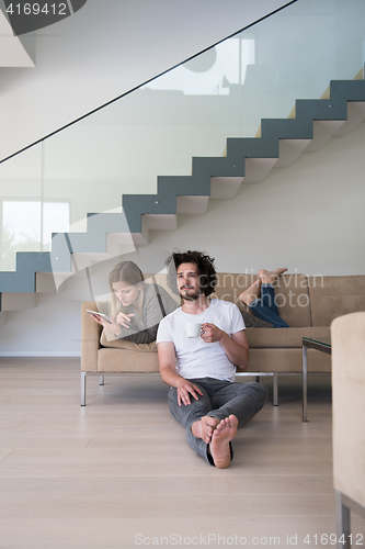 Image of couple relaxing at  home with tablet computers