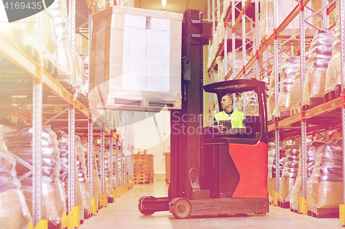 Image of man with tablet pc operating forklift at warehouse