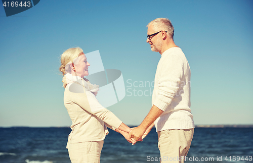Image of happy senior couple holding hands summer beach