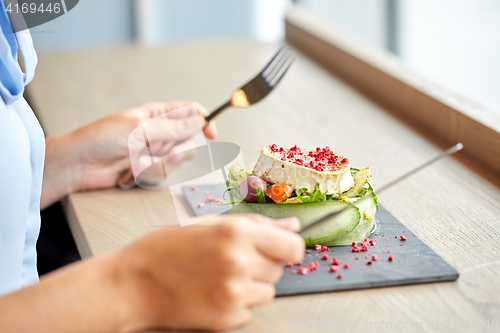 Image of woman eating goat cheese salad at restaurant