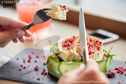 Image of woman eating goat cheese salad at restaurant