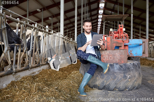 Image of young man with tablet pc and cows on dairy farm