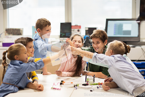 Image of happy children making high five at robotics school