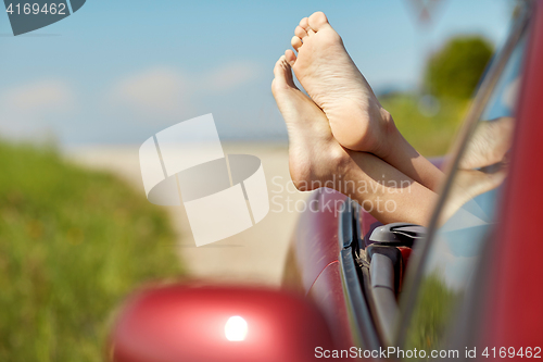 Image of feet of young woman in convertible car at summer 