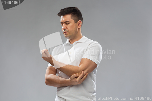 Image of unhappy man suffering from pain in hand