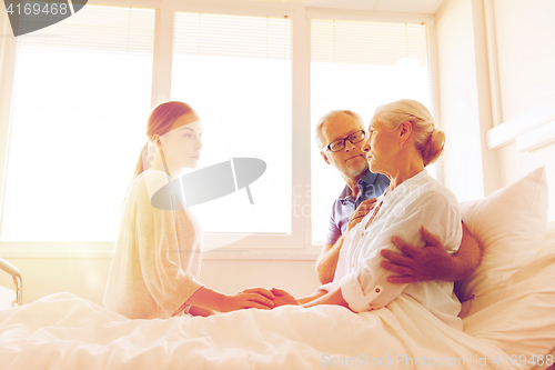 Image of family visiting ill senior woman at hospital