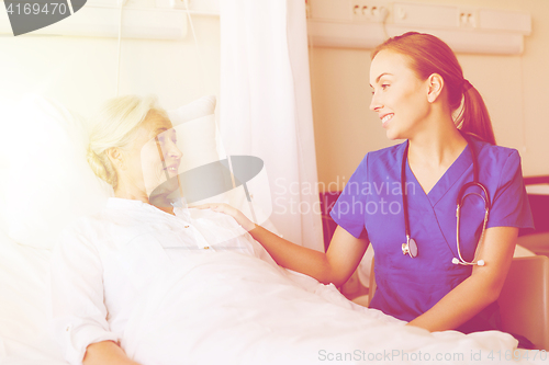 Image of doctor or nurse visiting senior woman at hospital