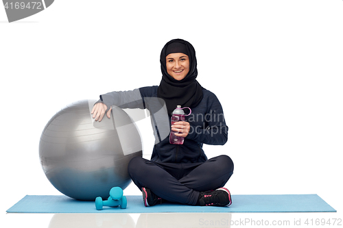 Image of muslim woman in hijab with fitness ball and bottle