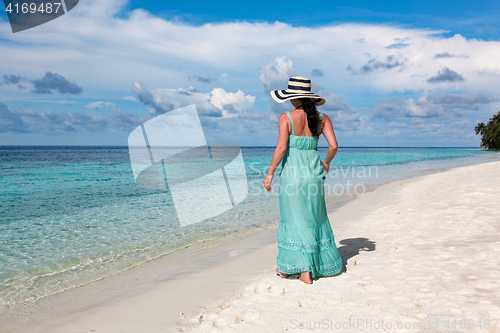 Image of Girl walking along a tropical beach in the Maldives.