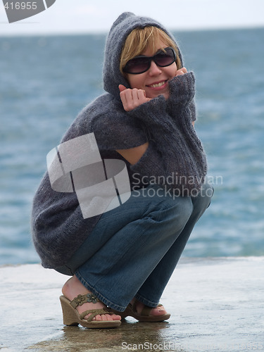 Image of Youn Lady in Hood Sitting near Sea