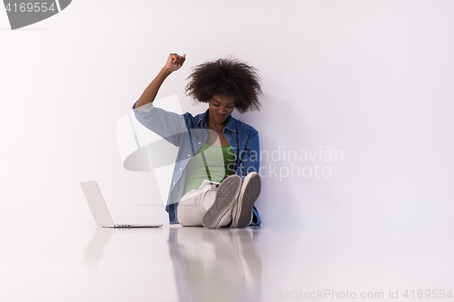 Image of african american woman sitting on floor with laptop