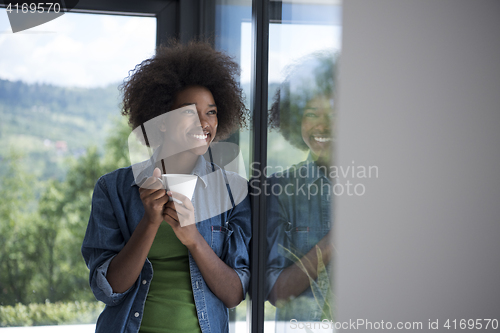 Image of African American woman drinking coffee looking out the window