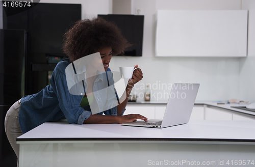 Image of smiling black woman in modern kitchen