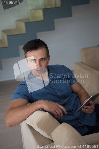 Image of young man using a tablet at home