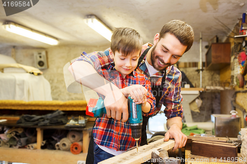 Image of father and son with drill working at workshop