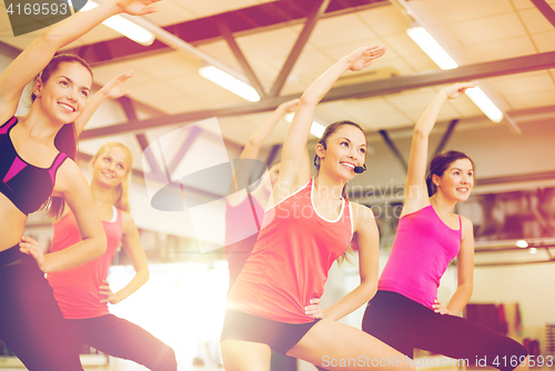 Image of group of smiling people stretching in the gym