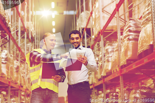 Image of worker and businessmen with clipboard at warehouse