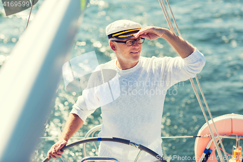 Image of senior man at helm on boat or yacht sailing in sea