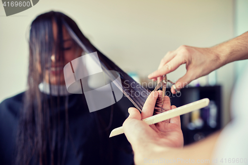 Image of happy woman with stylist cutting hair at salon