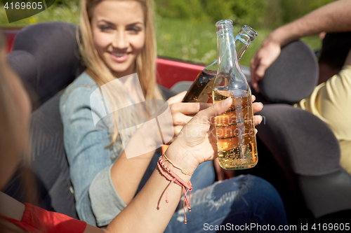 Image of happy young women with drinks in convertible car