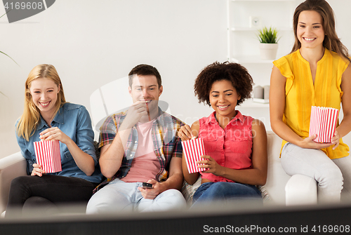 Image of happy friends with popcorn watching tv at home