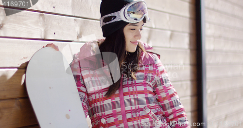 Image of Smiling woman in pink snowsuit with board