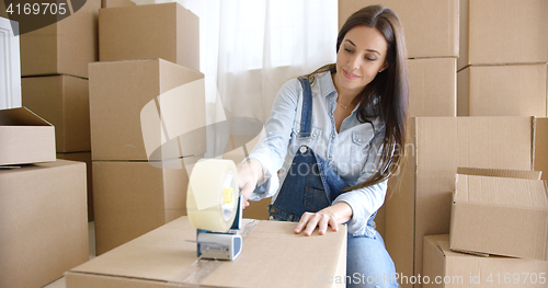 Image of Young woman moving home packing boxes