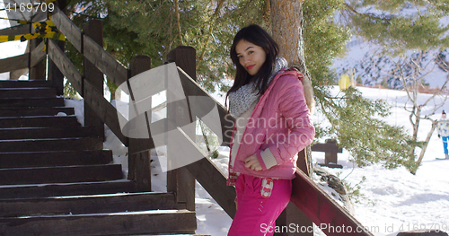 Image of Woman in pink snowsuit relaxing on stairs