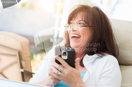 Image of Attractive Middle Aged Woman Laughing While Using Her Smart Phon