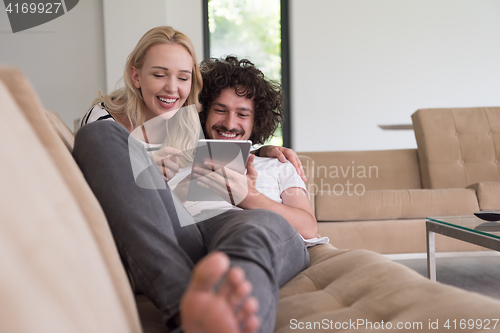 Image of couple relaxing at  home with tablet computers