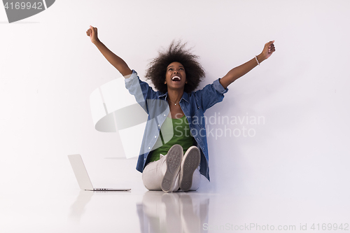 Image of african american woman sitting on floor with laptop