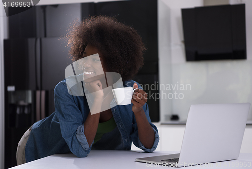 Image of smiling black woman in modern kitchen