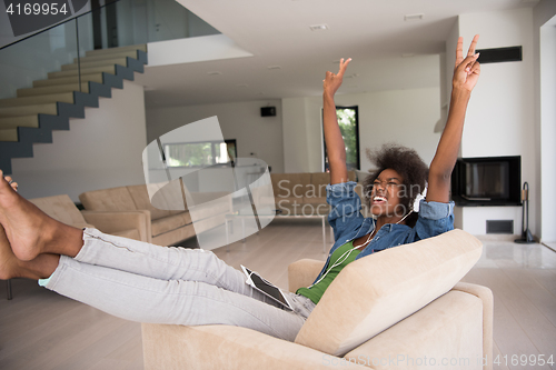 Image of African american woman at home in chair with tablet and head pho