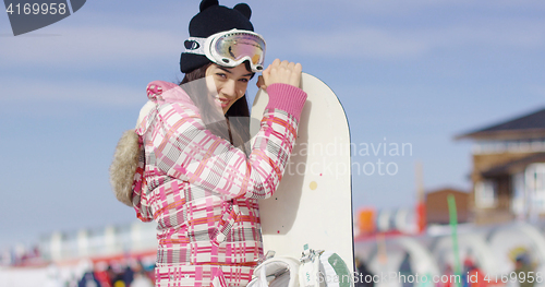Image of Cute asian female snowboarder relaxing on slope