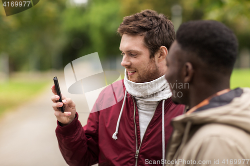 Image of happy friends with smartphone outdoors