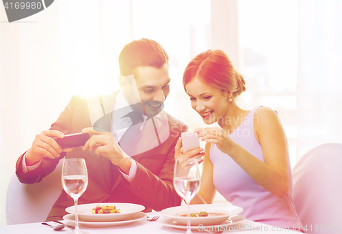 Image of smiling couple with appetizers and smartphones