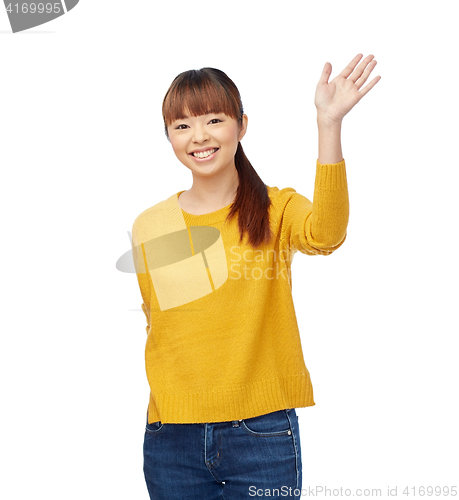 Image of happy asian young woman waving hand over white