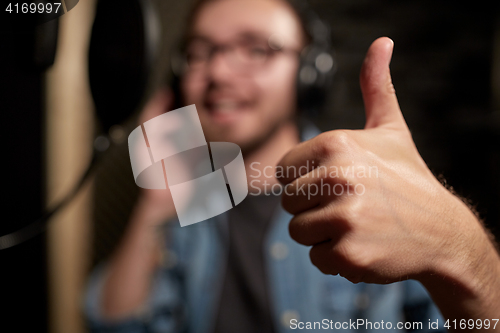 Image of singer showing thumbs up at sound recording studio