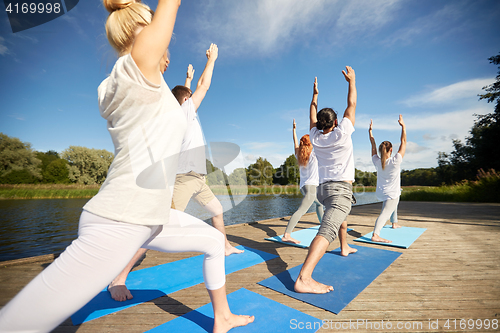 Image of group of people making yoga exercises outdoors