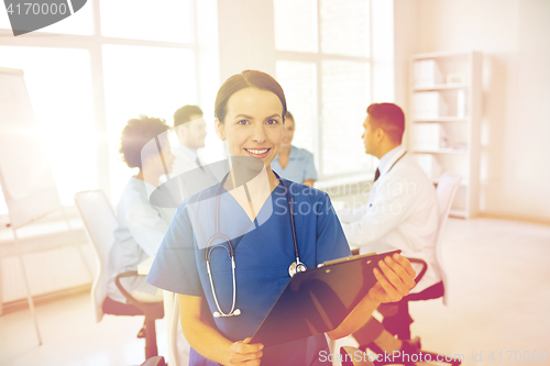 Image of happy doctor with clipboard over group of medics