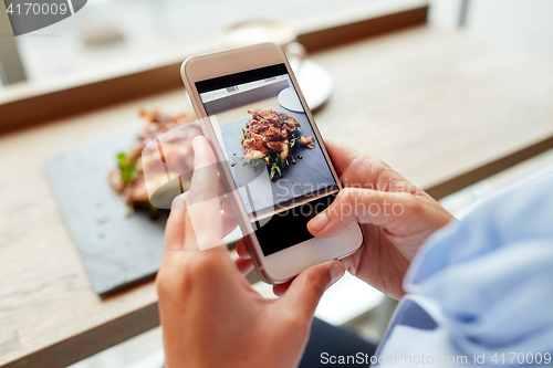 Image of hands with smartphone photographing food